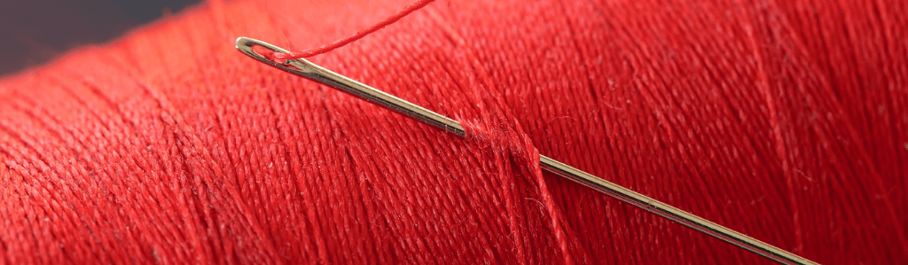 Roter Faden, der durch eine Nadel geführt wird. Symbol für klare Struktur und roten Faden auf einer Website