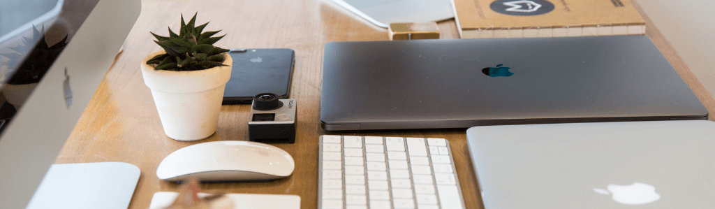 Moderner Schreibtisch mit Laptop, Tastatur und kleiner Pflanze als Symbol für eine erstellte Website und die späteren Pflegearbeiten.